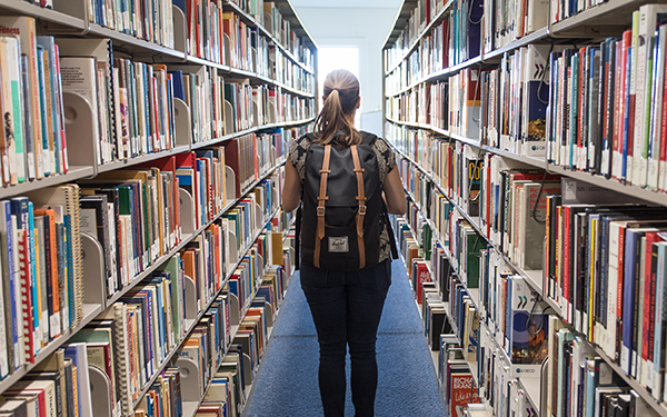 student stands with her back to camera among the stacks in the Dayton Memorial Library