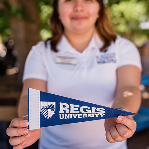 Regis staff member holds out a Regis University pennant