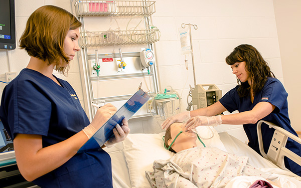 two nurses attend to a medical mannequin