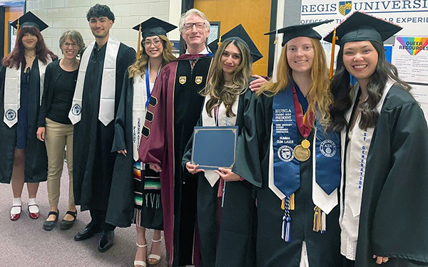 students, faculty and staff wearing their regalia line up in the hallway during a ceremony for the RU First Program in Claver Hall
