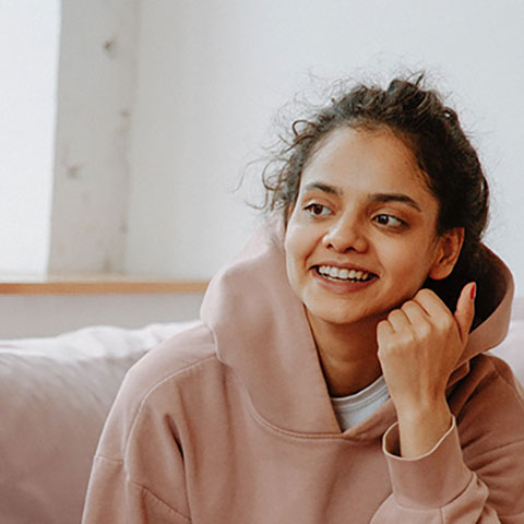 a student sits on a sofa smiling during a counseling session