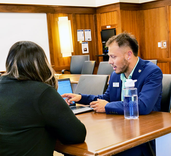 an Admissions staff member advises a prospective student at an Admissions event in the Board Room in Claver Hall on the Northwest Denver campus 