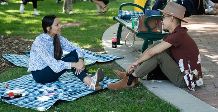 Two students sit on a blanket during a picnic on the quad at Blue and gold weekend