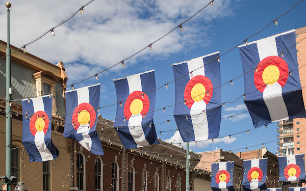 colorado flags flying from buildings in downtown Denver