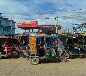 small, colorful golf-cart-like vehicles on a city road in Myanmar