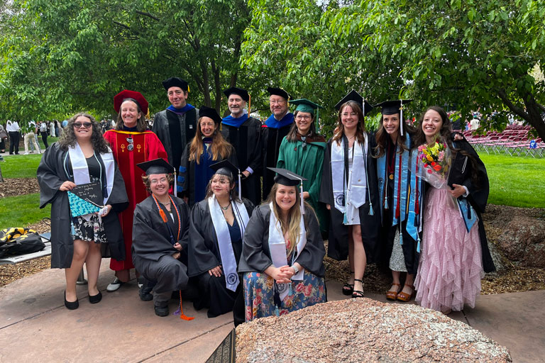 group of graduating students posed with several english department faculty members, all dressed in cap and gown