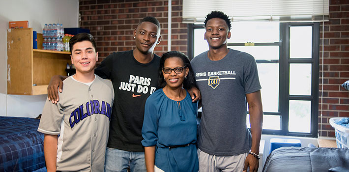 a proud mom stands by her son and his new roommates during move-in day on the Northwest Denver campus
