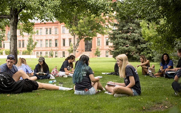 First-year students sit in small discussion groups on the grass on the Quad during new student orientation
