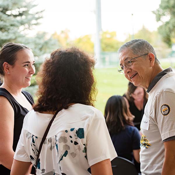 aceves talks to two attendees at Blue and Gold weekend outside on the quad