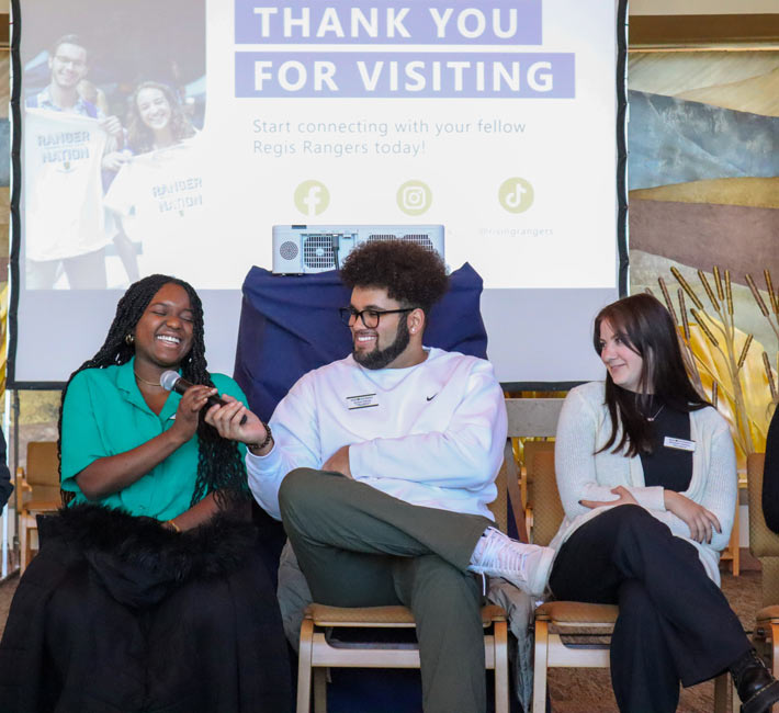 Three people sit down on chairs and are smiling