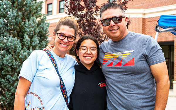 a new residential student and their parents embrace outside Clarke Hall on move-in day