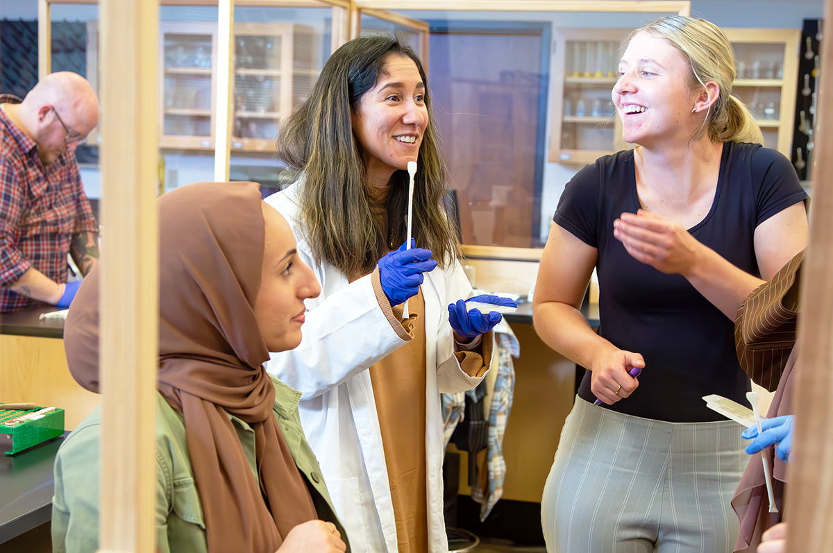 a group of pharmacy student smiles while working in the pharmacy lab on the Regis campus