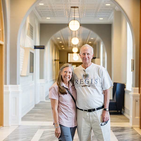 two alumni embrace while standing in the light and airy second floor hallway in main hall