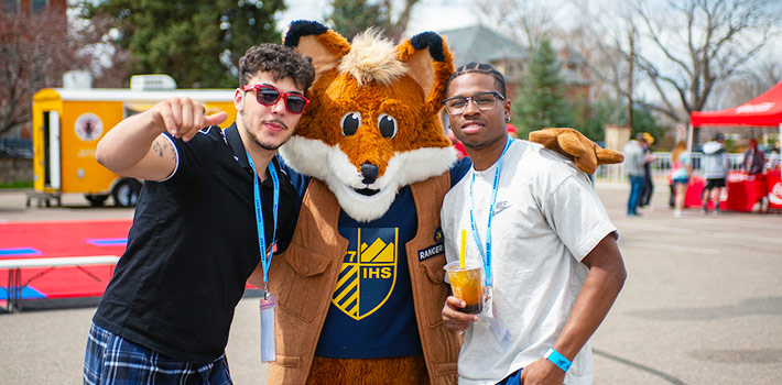 two students pose with Regi the Fox during Ranger Day festivities on the Regis campus