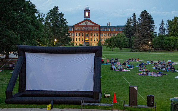 Main Hall in the background. People sitting on blankets looking at an inflatable screen