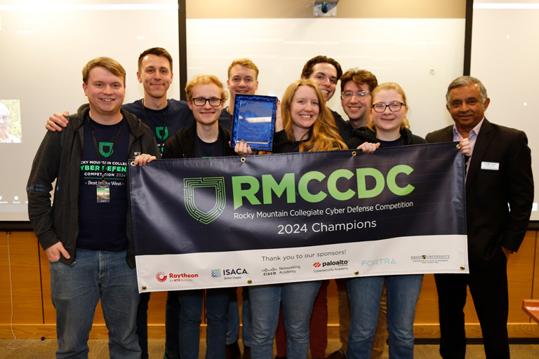 The BYU team holds the winners banner with academic dean of Anderson College of Business and Computing, Madhu Rao