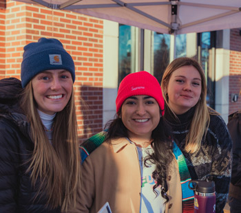 Three students pose together for a photo in winter clothing