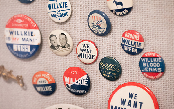 A collection of vintage political campaign buttons displayed on a fabric-covered board. The buttons prominently promote Wendell Willkie, a U.S. presidential candidate in the 1940 election. They bear slogans like "Willkie for President," "We Want Willkie," and "Willkie is My Man!" Some buttons include additional imagery or references to running mates and party affiliations. 