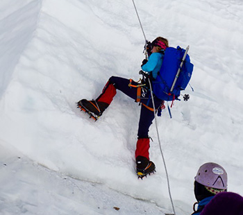 Roger holding onto a rope while climbing the side of a mountain