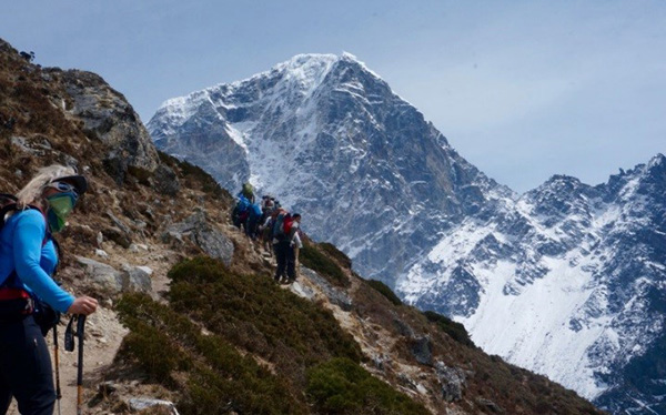 Group of people walk on a windy trail up a mountain