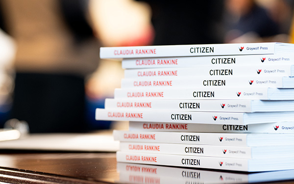 A stack of Radkine's book, Citizen: An American Lyric, sitting on a desk, slightly askew, in sharp focus, while the background is blurred