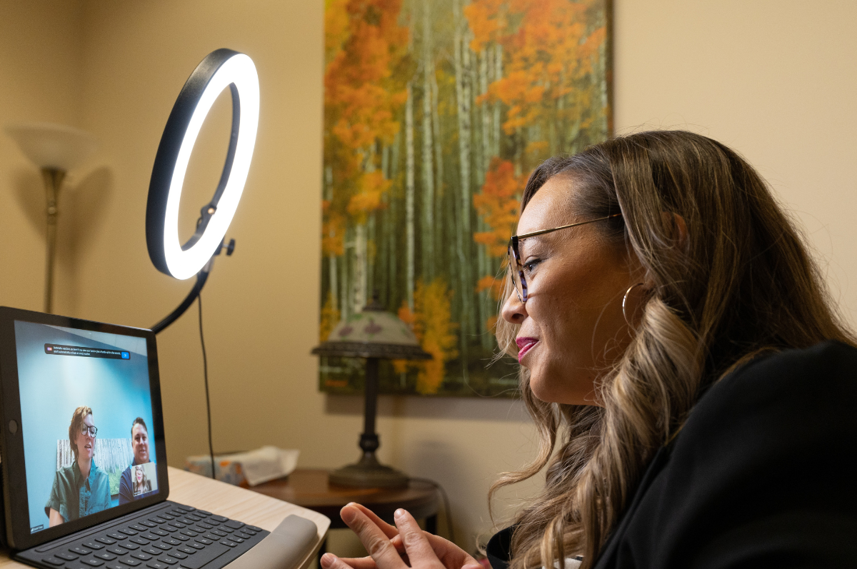 therapist speaks to clients over on a computer screen