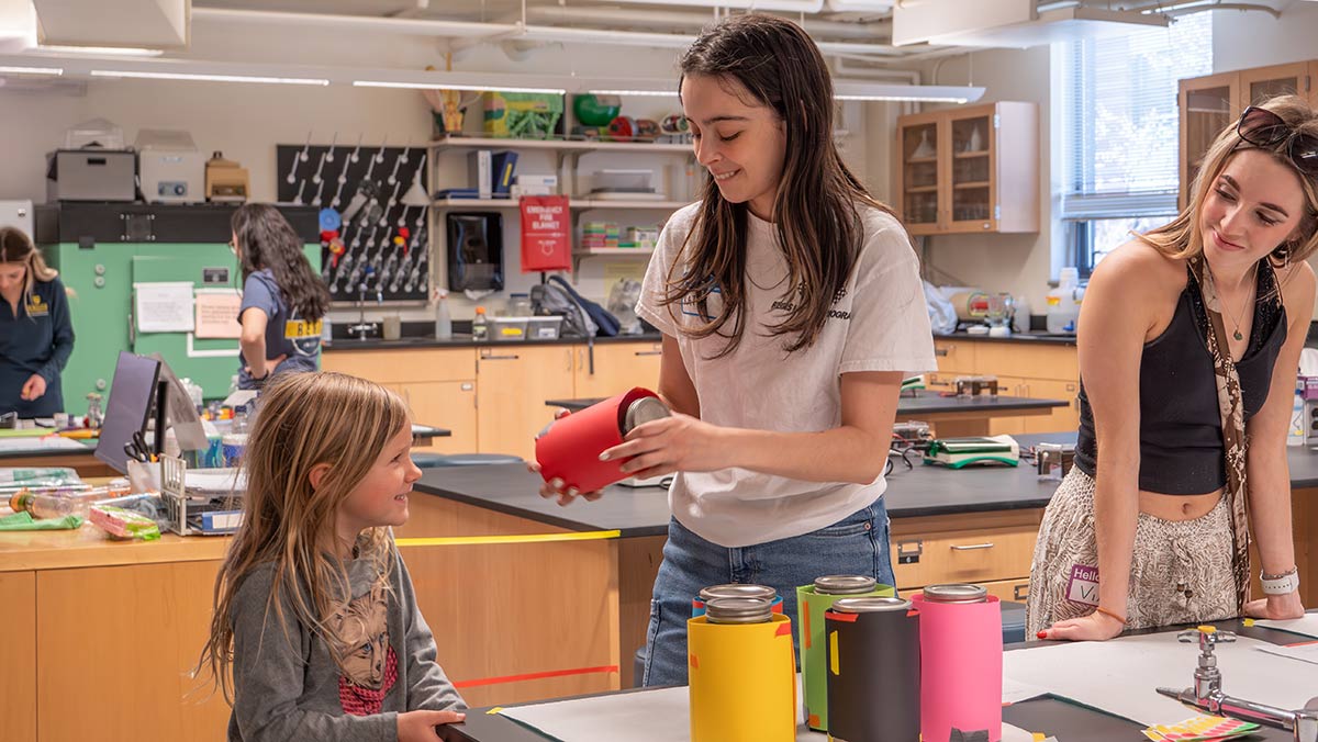 Isabella and Katelyn De Leon help a young science student with an experiment in a biology lab on the Northwest Denver campus