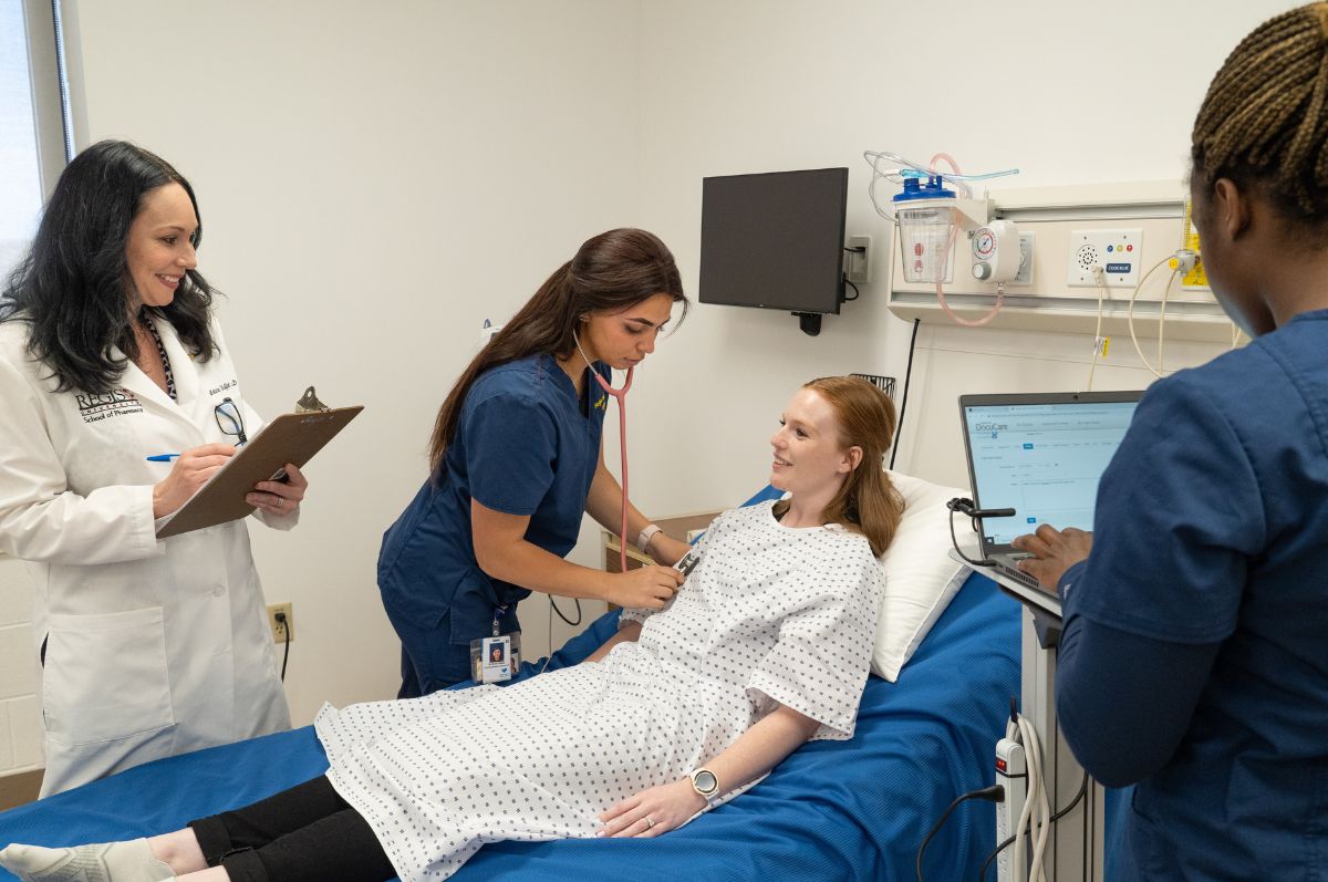 students attend to a patient in a nursing lab