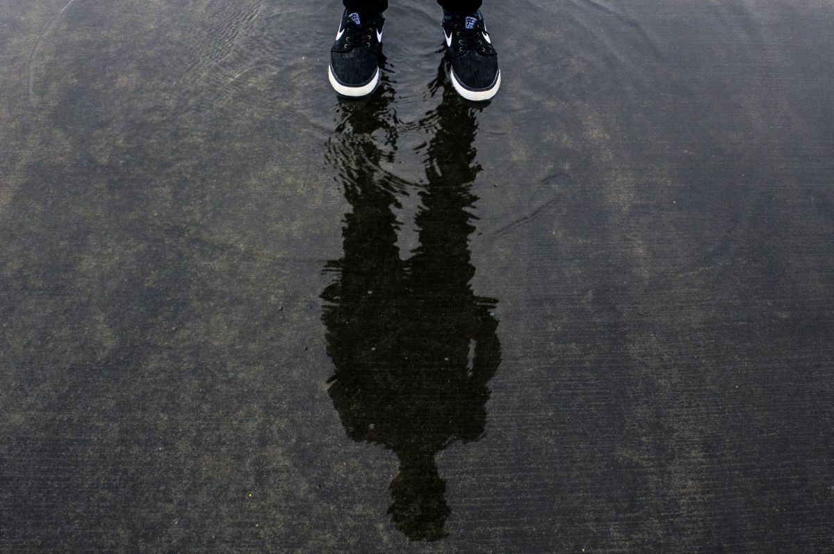 Stock photo of a person's reflection in a puddle.